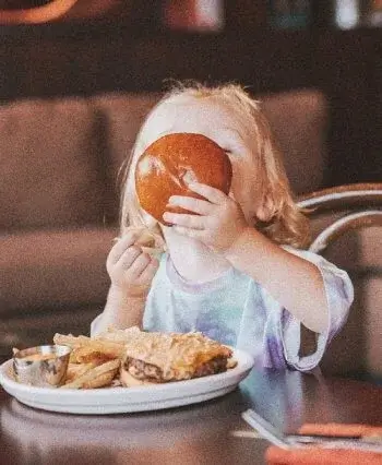Blond kid eating a cheeseburger
